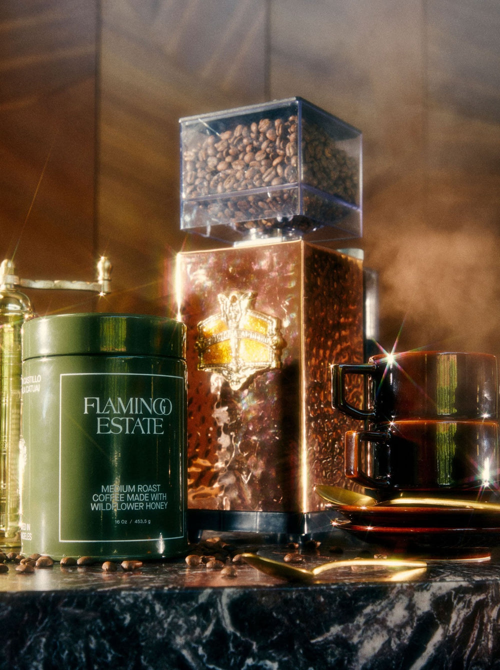 Coffee beans stored in a transparent container atop a copper grinder.