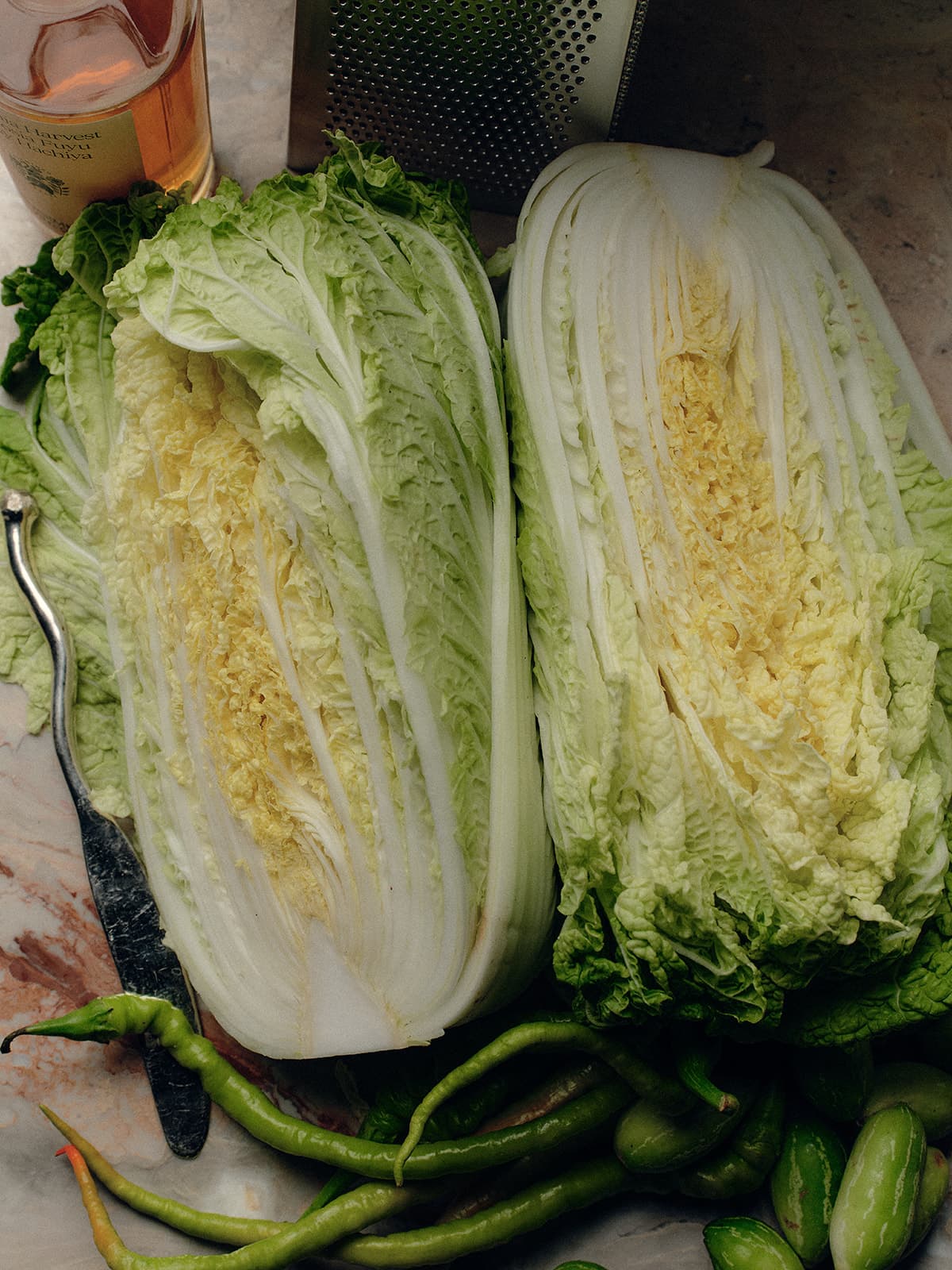Halved Green Cabbage Next To Flamingo Estate's Winter Harvest Persimmon Vinegar And Other Kitchen Items