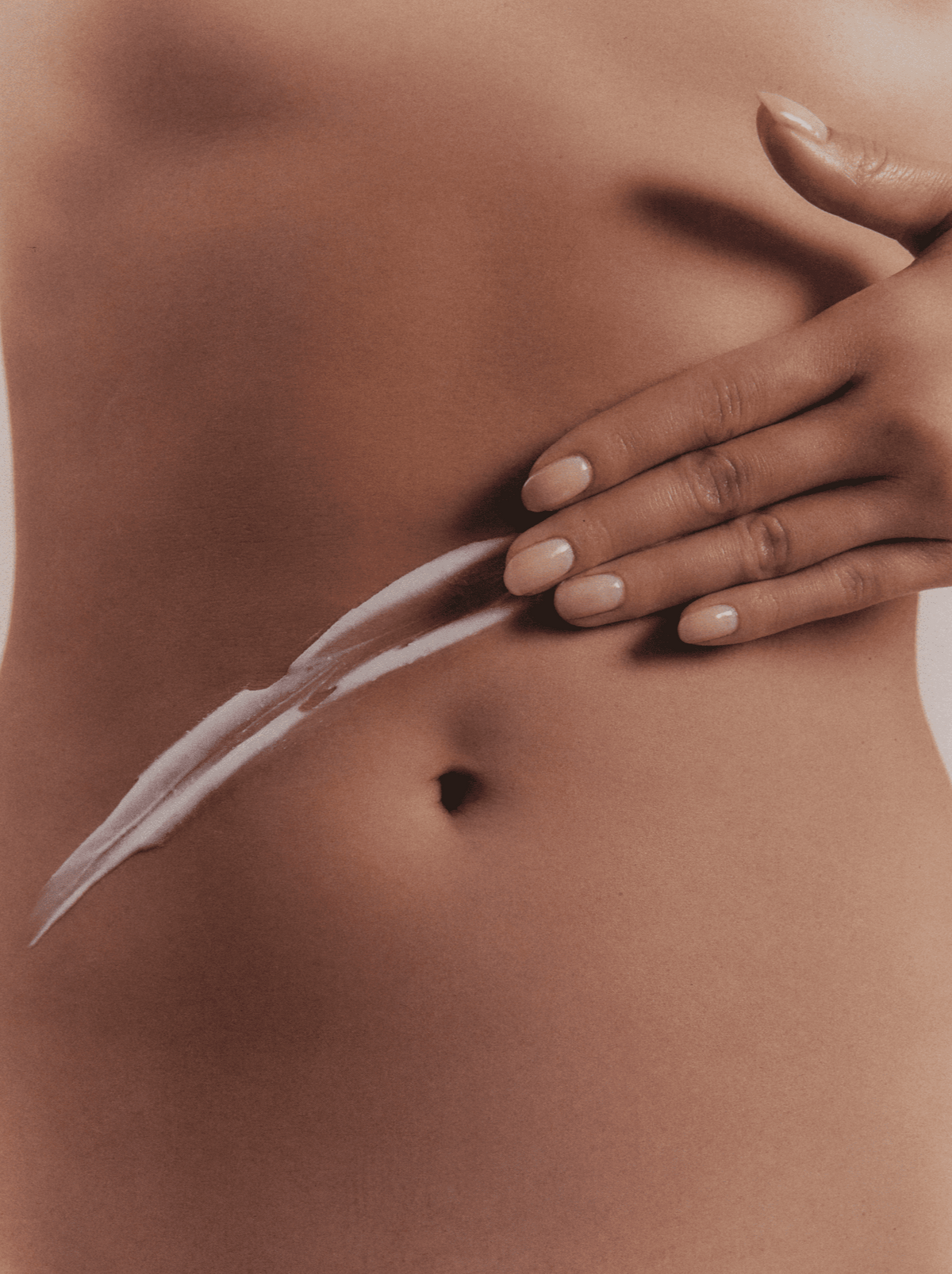 Woman's Hand Leaving A Trail Of Body Lotion On Her Tummy