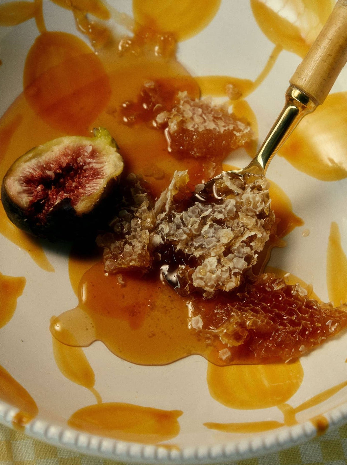 A partially eaten fig rests on a plate, with a fork holding a piece of the fig.