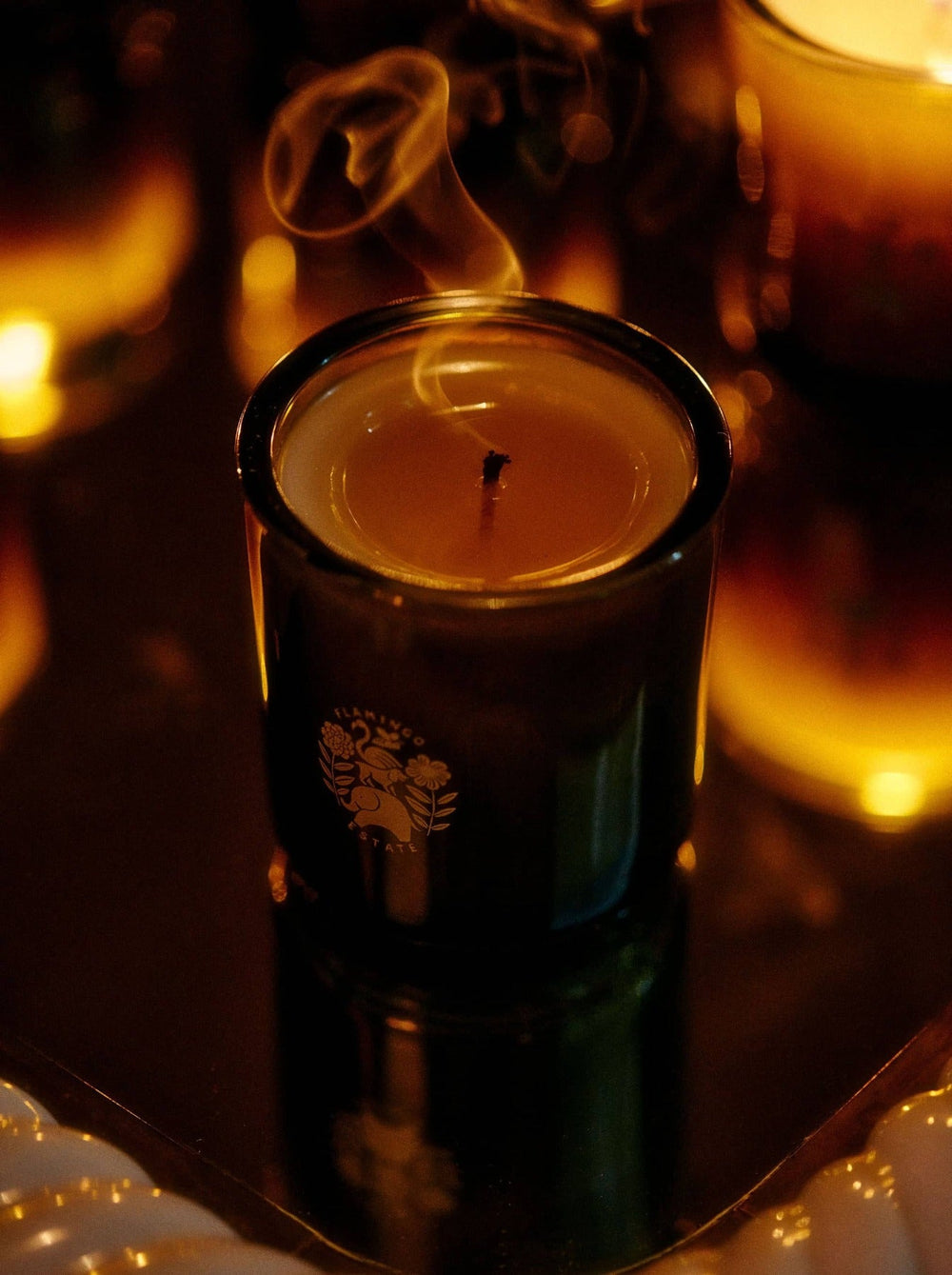 Candle releases smoke into dimly lit surroundings.