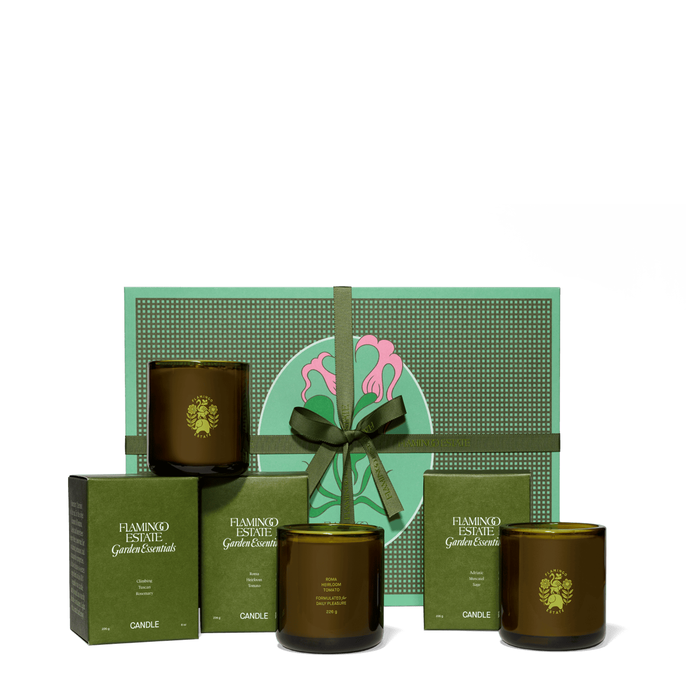 Three Flamingo Estate Garden Essentials Candles And Packaging Displayed In Front Of A Green Gift Set Box