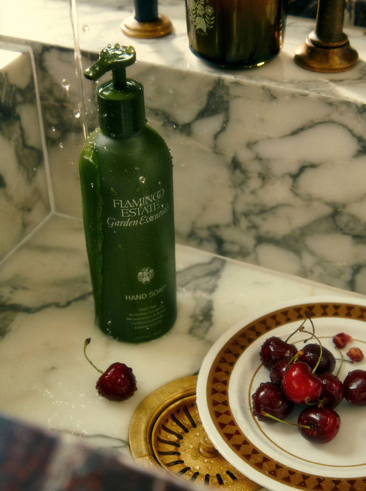 Bottle Of Garden Essentials Hand Soap Next to A Dish of Cherries In A Marble Sink