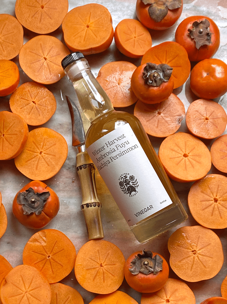 Bottle Of Flamingo Estate Fuyu Vinegar With Halved Persimmons